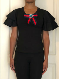 Black blouse with short ruffled puff sleeves and jeweled red/blue ribbon.